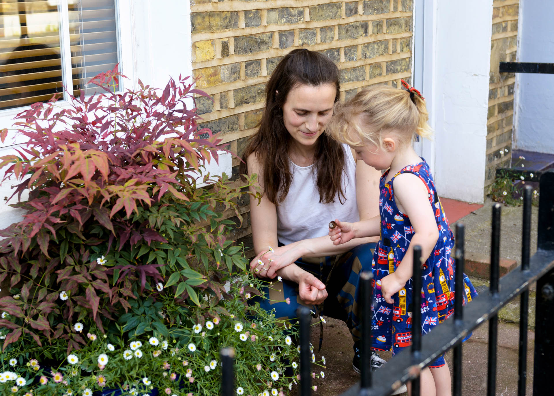 family photo of toddler picking grasses wearing a dress with busses in South London