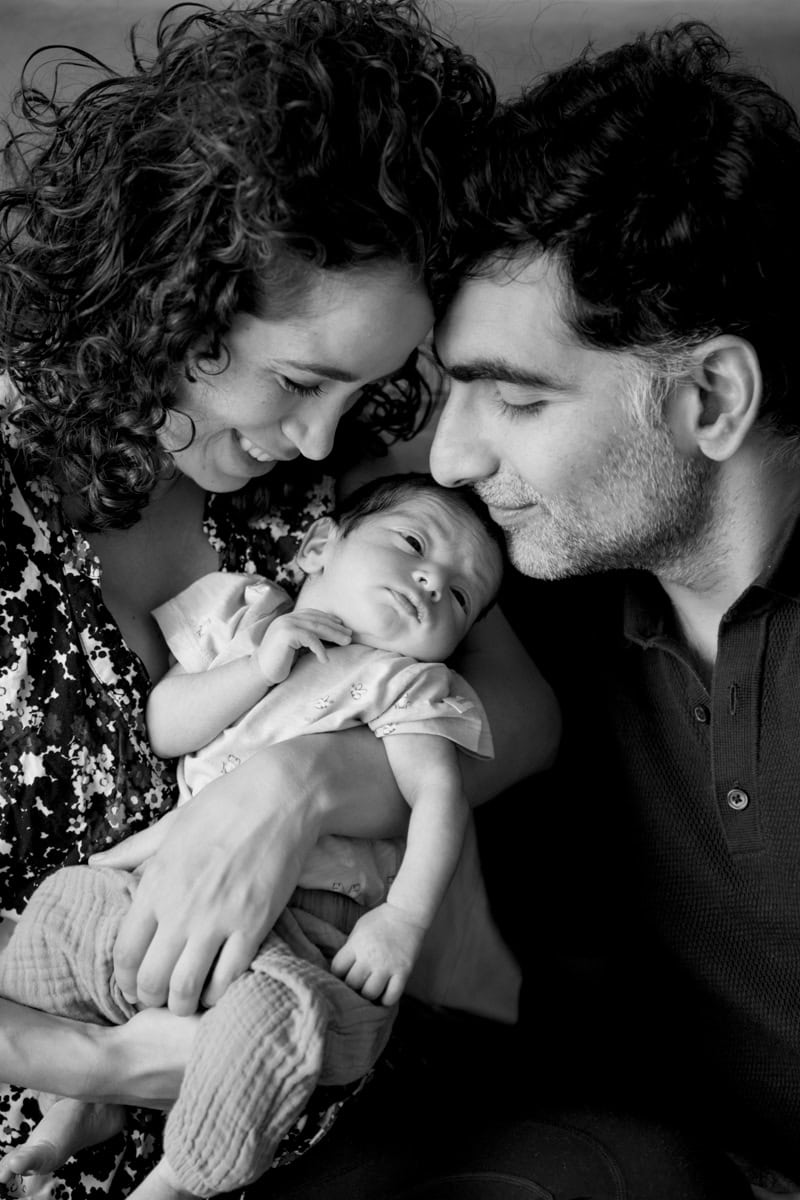 a family photograph showing a couple gazing down at their newborn in black and white. Image by Molly Rhianon Photography. 