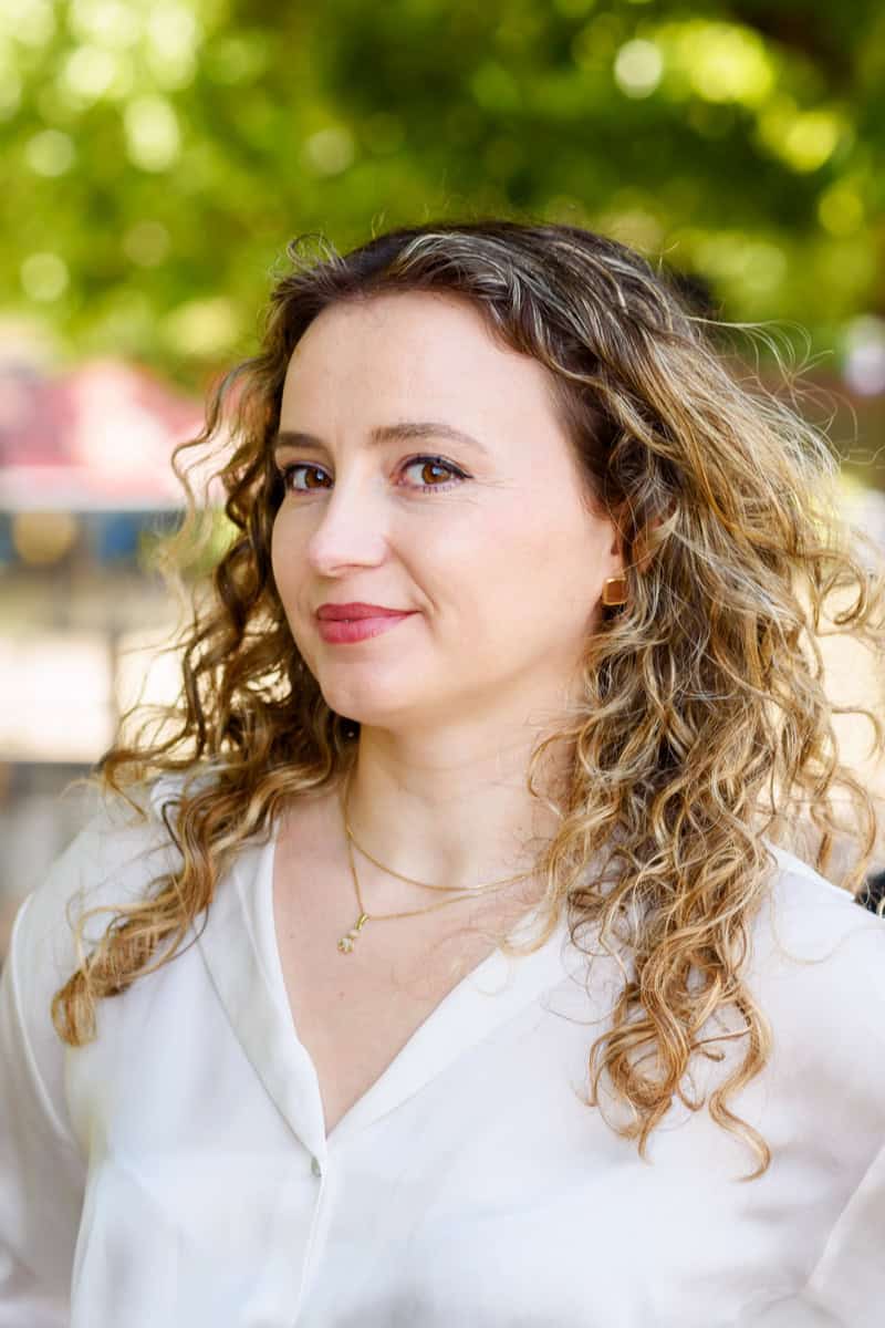 a headshot photo of a female business owner on the Southbank. She is wearing a white shirt and gold accessories and looking into the camera. Photo by Molly Rhianon photography